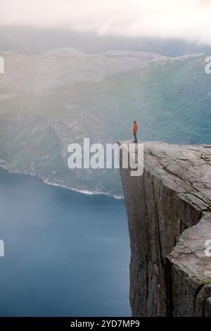 Preikestolen, Norwegen, Eine Einzelperson steht am Rande einer steilen Klippe mit Blick auf einen nebeligen Fjord in Norwegen. Die Weite des Stockfoto