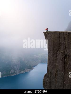 Ein atemberaubender Blick von der Spitze der Preikestolen Klippe in Norwegen, mit zwei Figuren am Rand mit Blick auf die Stockfoto