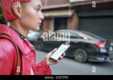 Traveler Gen z Mädchen Ledermode mit Punk asiatische Frau Tourist in der Stadt Straße Suche Standort in Karte Anwendung Online Smartphone mit GPS na Stockfoto