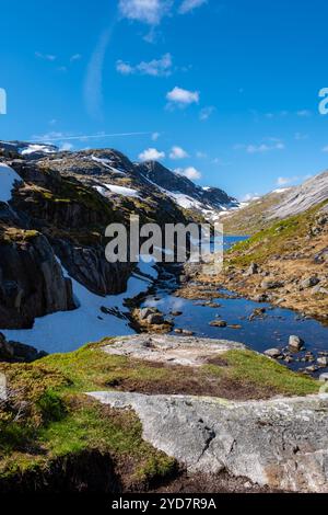 Kjeragbolten Norway Ein sich windender Fluss fließt durch ein malerisches Tal in den norwegischen Bergen, umgeben von schneebedeckten Gipfeln und Stockfoto