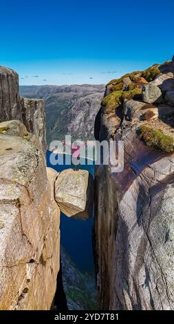 Ein einsamer Wanderer steht am Rande der Kjeragbolten, Norwegen Klippe in Norwegen und genießt den atemberaubenden Blick auf den Fjord darunter Stockfoto