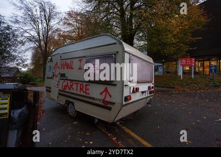 Carmarthen, Großbritannien. 25. Oktober 2024. Eine Karawane wird vor den walisischen Regierungsbüros in Carmarthen verlassen, die mit Graffiti befüllt ist, die die Menschen zum Recht auf Wohnung auffordern, nachdem die walisische Regierung vermeintlich nicht aktiv war. Gruffydd Thomas/Alamy Stockfoto