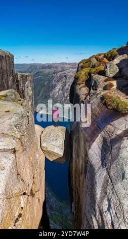 Eine Einzelfigur steht am Rande einer Klippe bei Preikestolen, Norwegen, und blickt über die weite Weite darunter Stockfoto