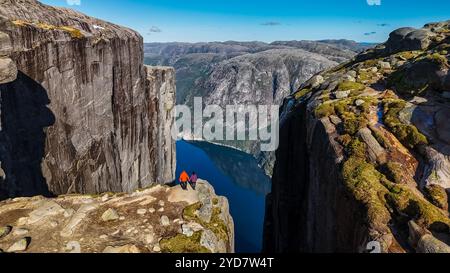 Zwei Personen stehen am Rande des Kjeragbolten, Norway Kanzel Rock in Norwegen, mit Blick auf die atemberaubende Landschaft. Ein paar Männer und Frauen kommen zu Besuch Stockfoto