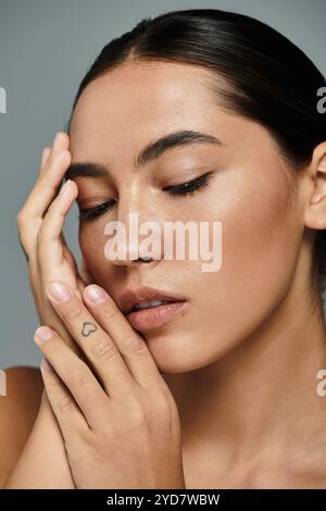 Eine anmutige Frau berührt sanft ihr Gesicht und strahlt innen Ruhe und natürliche Ausstrahlung aus. Stockfoto