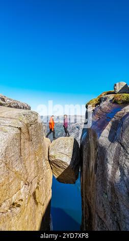 Zwei Wanderer stehen auf Kjeragbolten in Norwegen, einer Felsformation, die über eine steile Klippe in Norwegen ragt. Das legendäre Wahrzeichen bietet Stockfoto