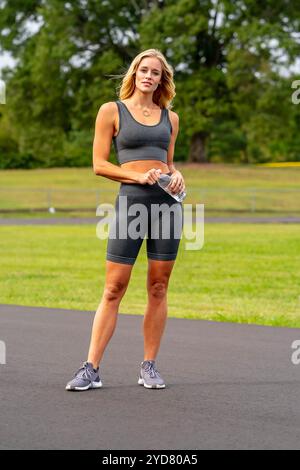 Ein atemberaubendes, blondes Fitnessmodell bereitet sich auf ein Workout vor, das Selbstvertrauen und Entschlossenheit bei jeder Bewegung ausstrahlt. Stockfoto