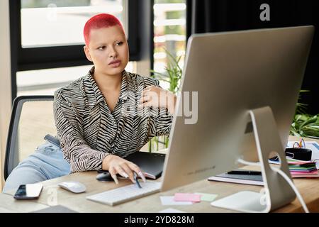 Die schöne kahlköpfige Frau reflektiert die Arbeit, während sie bei Tageslicht an einem stilvollen Schreibtisch sitzt. Stockfoto