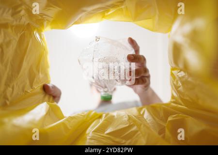 Bild aus dem gelben Recyclingbeutel eines Mannes, der leere Plastikflasche in den Recyclingbehälter wirft Home Recycle ECO Green Zero Concept Stockfoto