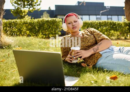 Eine kahlköpfige Frau genießt einen ruhigen Moment im Freien, während sie mit ihrem Laptop und Kaffee interagiert. Stockfoto