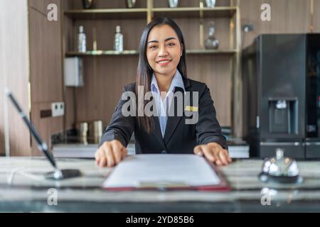 Schöne asiatische Hotelrezeptionistin in Uniformen am Schreibtisch in der Lobby FriendlyÂ und Empfangspersonal am Hotelrezeptionsschalter. Stockfoto