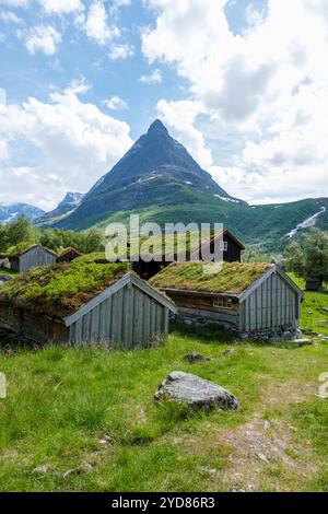 Ein Blick auf traditionelle norwegische Hütten mit Grasdächern, eingebettet im Tal unterhalb eines majestätischen Berggipfels. Innerdalen Valley Norwegen Stockfoto