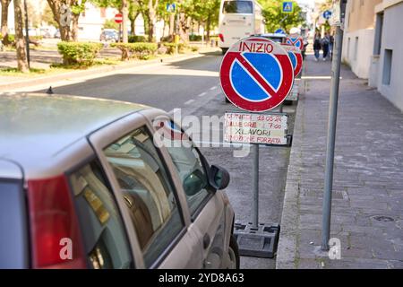 Ancona, Italien - 10. Mai 2024: Ein Auto parkt in Italien in einem Parkverbot, gekennzeichnet durch ein Verkehrsschild mit dem Hinweis auf Bauarbeiten und eine drohende Zwangsentfernung *** ein Auto parkt in Italien in einem Parkverbot, gekennzeichnet durch ein Verkehrsschild mit dem Hinweis auf Bauarbeiten und einer drohenden Zwangsentfernung Stockfoto