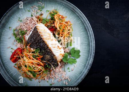 Gebratenes Kabeljau-Filet mit Papaya-Som-tam-Salat und rotem Reis serviert als Blick von oben auf nordischem Design-Teller mit Kopierraum rechts Stockfoto