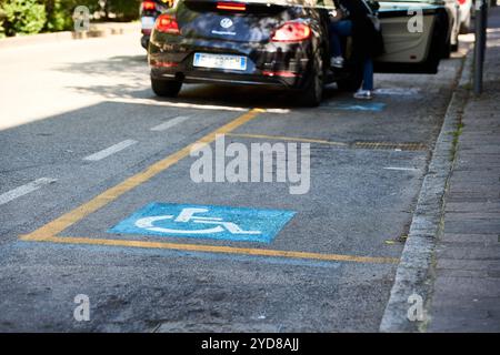 Ancona, Italien - 10. Mai 2024: Ein Auto parkt in Italien auf einem Behindertenparkplatz, der durch blaue Markierungen und das Rollstuhlsymbol gekennzeichnet ist *** ein Auto parkt in Italien auf einem Behindertenparkplatz, der durch blaue Markierungen und das Rollstuhlsymbol gekennzeichnet ist Stockfoto