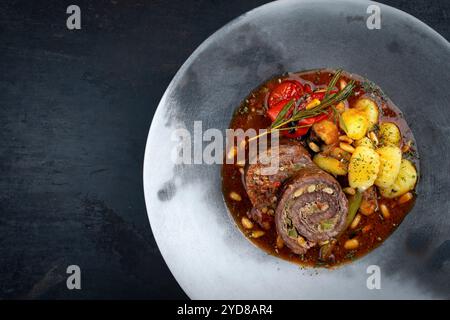 Traditionelle langsam gekochte deutsche Wagyu-Rindfleischrouladen mit Gemüse und Gnocchi serviert in scharfer Rotweinsauce als Blick von oben in A No Stockfoto