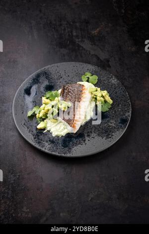 Gebratenes Kabeljaufilet mit Kartoffelpüree und Avocado wurde als Nahaufnahme auf nordischem Design-Teller mit Kopierraum serviert Stockfoto