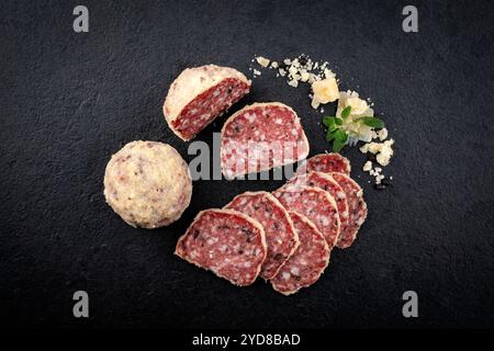 Traditionelle italienische Saltufo-Salami mit Parmesan-Beschichtung und Trüffel serviert als Blick von oben auf einem schwarzen Design-Tablett Stockfoto