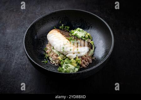 Gebratenes Kabeljaufilet mit Avocadocreme und gekochtem Reis wurde als Nahaufnahme auf nordischem Design-Teller mit Kopierraum serviert Stockfoto