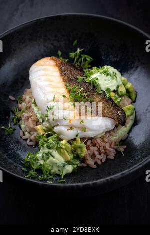 Gebratenes Kabeljaufilet mit Avocadocreme und gekochtem Reis wurde als Nahaufnahme auf nordischem Design-Teller mit Kopierraum serviert Stockfoto