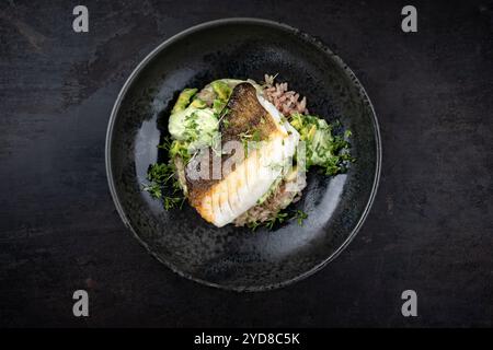 Gebratenes Kabeljaufilet mit Avocadocreme und gekochtem Reis wurde als Draufsicht auf nordischem Design-Teller mit Kopierraum serviert Stockfoto