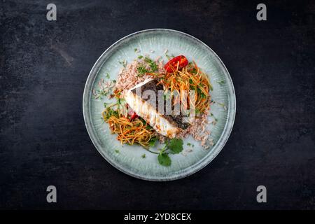 Gebratenes Kabeljau-Filet mit Papaya-Som-tam-Salat und rotem Reis serviert als Blick von oben auf nordischem Design-Teller mit Kopierraum Stockfoto