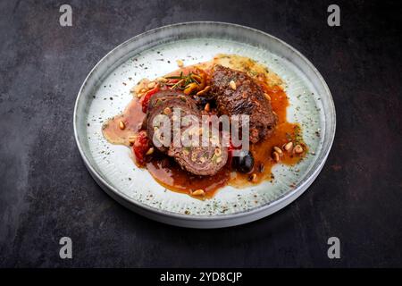 Traditionelle langsam gekochte deutsche Wagyu-Rinderrouladen mit Oliven und Pinienkernen, serviert in scharfer Rotweinsauce als Nahaufnahme in einem NOR Stockfoto