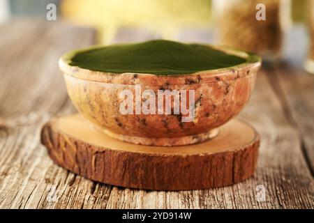 Grünes Chlorella-Algenpulver in einer Schüssel auf einem Holztisch draußen Stockfoto