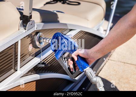 Mann betankt Boot am Yachthafen. Gaspumpendüse füllt Ponton Party Boot Kraftstofftank. Stockfoto