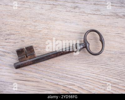 Ein alter Eisenschlüssel auf hölzernem Hintergrund. Blick von oben. Stockfoto
