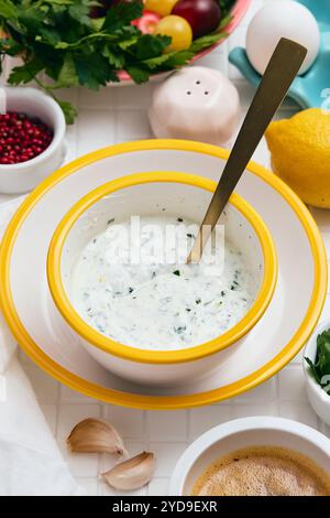 Griechische Joghurtsauce mit Zitrone, Knoblauch und Petersilie. Eine Schüssel mit einem Löffel voller Soße. Stockfoto