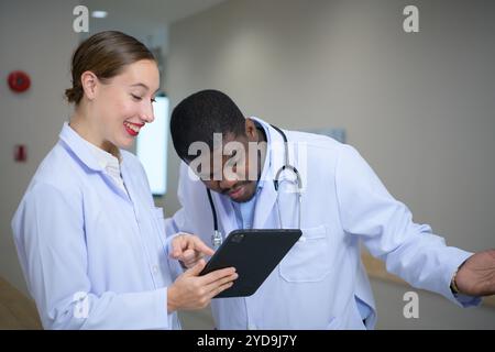 Beide Ärzte analysieren die MRT-Ergebnisse des Patienten auf einem Tablet, um Ideen auszutauschen und neue Informationen für den Patienten zu finden Stockfoto