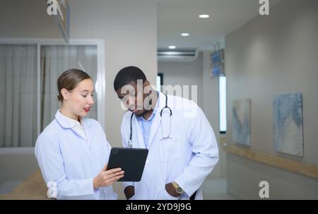 Beide Ärzte analysieren die MRT-Ergebnisse des Patienten auf einem Tablet, um Ideen auszutauschen und neue Informationen für den Patienten zu finden Stockfoto