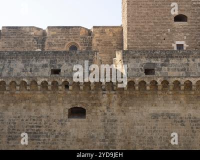 Eine Steinmauer, Zinnen, Kanonenschlitze und ein Teil eines Turms auf der Burg Bari in Italien. Stockfoto