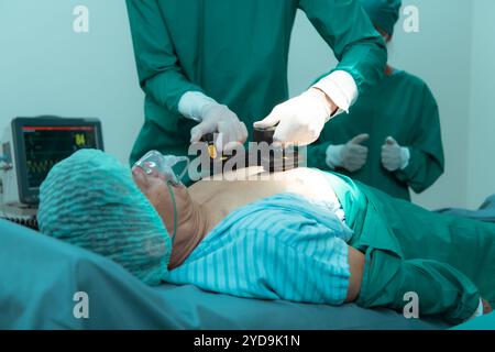 Ein Ärzteteam im OP führt bei einem Patienten, der an einem Schock aufgrund einer Herzinsuffizienz leidet, eine HLW durch. Stockfoto