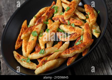 Nahaufnahme von Schupfnudeln, Fingernudel, dicken deutschen Kartoffelnudeln, Klößchen in einer Pfanne auf rustikalem Holztisch, holländischer Blickwinkel Stockfoto