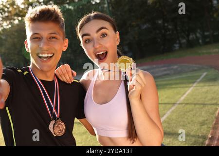 Porträt glücklicher Gewinner mit Medaillen im Stadion. Leerzeichen für Text Stockfoto