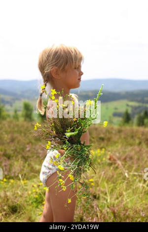 Lächelndes kleines Mädchen mit Blumenstrauß auf dem Feld Stockfoto