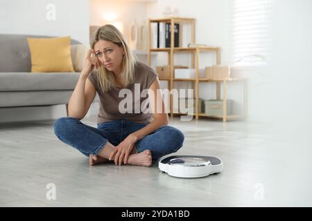 Wechseljahre, Gewichtszunahme. Besorgte Frau, die zu Hause in der Nähe der Waage sitzt Stockfoto