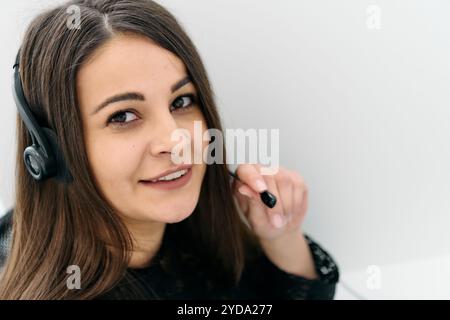 Benutzerfreundlicher Call Center-Agent, der eingehende Anrufe mit einem Headset entgegennimmt, das den Remote-Kundendienst bereitstellt. Stockfoto