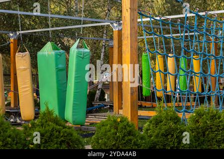 Farbenfroher Hindernisplatz mit Hängekissen und Netzkletterbereich im Outdoor-Abenteuerpark. Körperliche Herausforderung und Outdoor-Aktivitäten Stockfoto