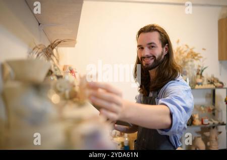 Geschäftsmann, der ein kleines Keramikgeschäft hat und Produkte im Geschäft überprüft, um sie für den Verkauf vorzubereiten oder mehr Produkte zu bestellen Stockfoto