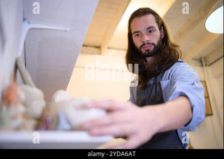 Geschäftsmann, der ein kleines Keramikgeschäft hat und Produkte im Geschäft überprüft, um sie für den Verkauf vorzubereiten oder mehr Produkte zu bestellen Stockfoto