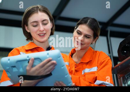 Beide Frauen in einer Elektronikfabrik, die eine Steuerung der Produktionslinie verwendet, und empfehlen Kollegen, dieses Werkzeug zu verwenden Stockfoto