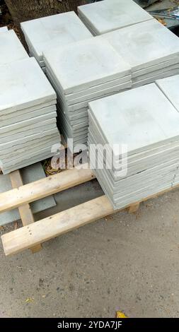 Mehrere Stapel Betonplatten sind im Freien auf Holzpaletten angeordnet, die ein Baustoffkonzept darstellen. Stockfoto