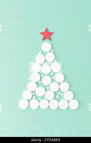 Weihnachtsbaum aus weißen Pillen mit Stern oben, flach auf grünem Hintergrund. Medizinisches Urlaubskonzept, Kopierraum. Gesundheit und Wellness Thema, festlich Stockfoto