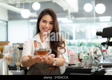 Die Barista-Frau hat den Tee für den Gast fertig gemacht und ist bereit, ihn zu servieren. Stockfoto