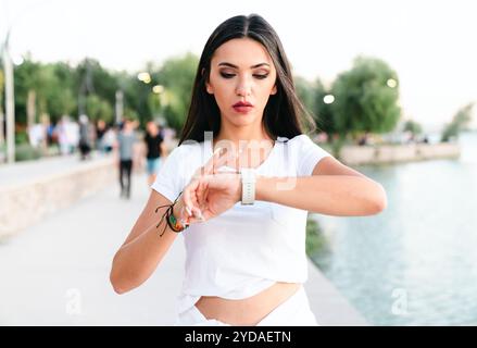 Frau überprüft ihre körperliche Aktivität auf Smartwatch. Junge Sportlerin, die während des Trainings auf Aktivitätstracker blickt. Stockfoto