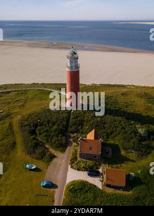 Ein Blick aus der Vogelperspektive zeigt einen Leuchtturm, der hoch am Sandstrand von Texel, Niederlande, steht und als Leuchtfeuer für das Segeln dient Stockfoto