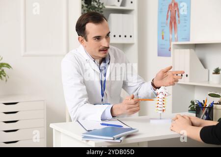 Arzt erklärt Wirbelsäulenanatomie mit Wirbelsäulenmodell dem Patienten in der Klinik Stockfoto